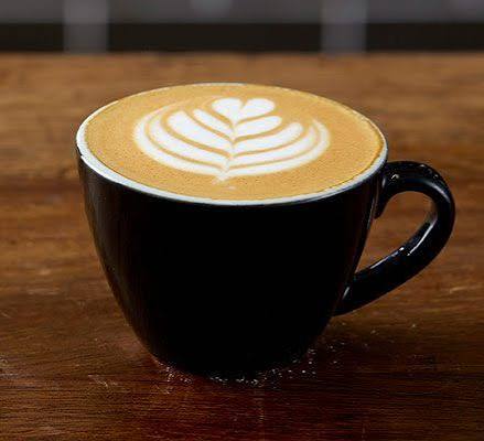 Oat milk flat white with beautiful latte art in a black cup